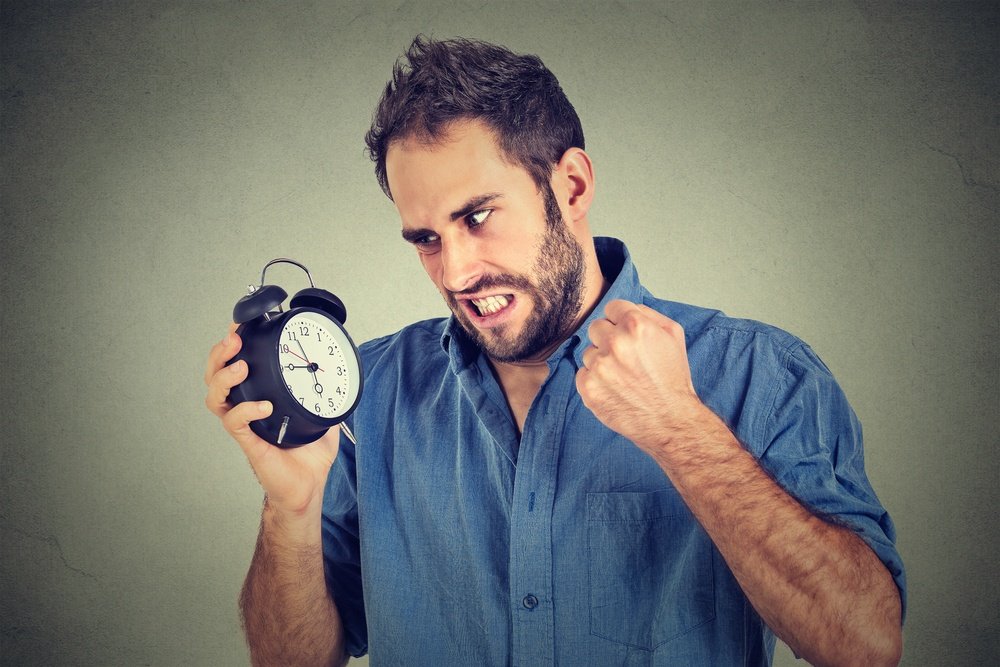 Image of a man looking angerly at an alarm clock