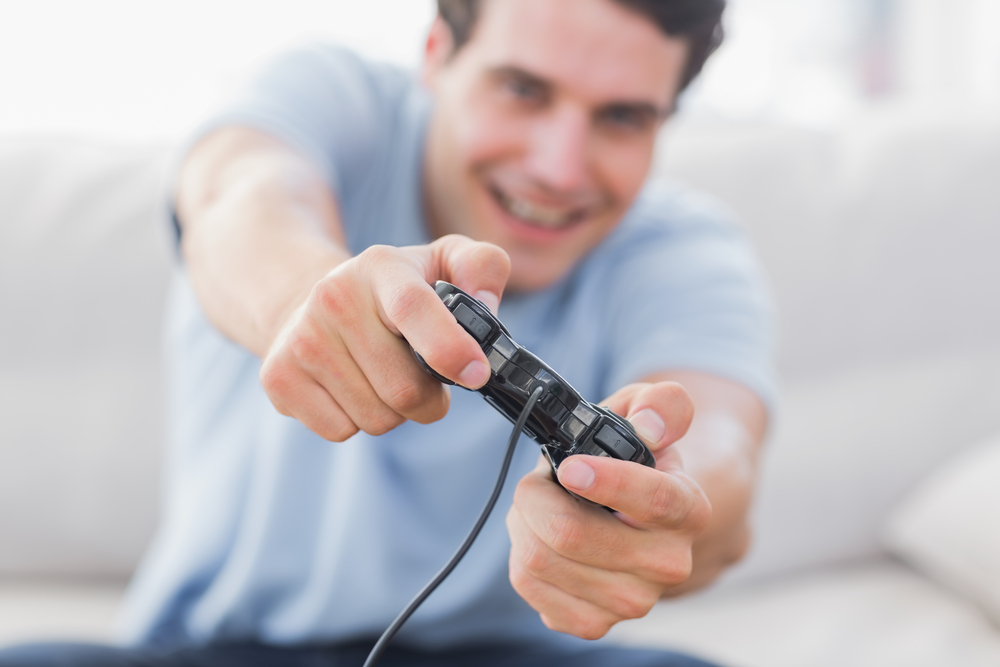 Image of a Man playing video games on a couch
