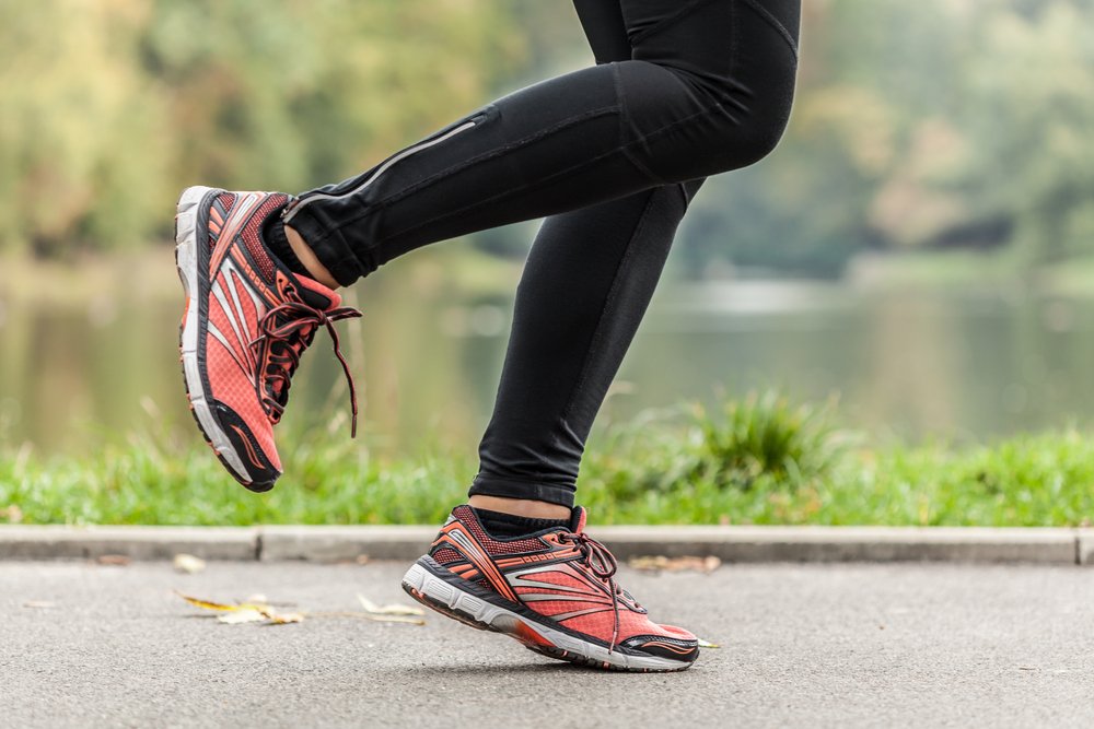 Image of a person running with black pants and red running shoes