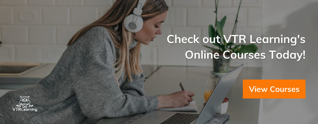 Woman with headphones leaning over a desk and taking notes while taking online courses on a laptop